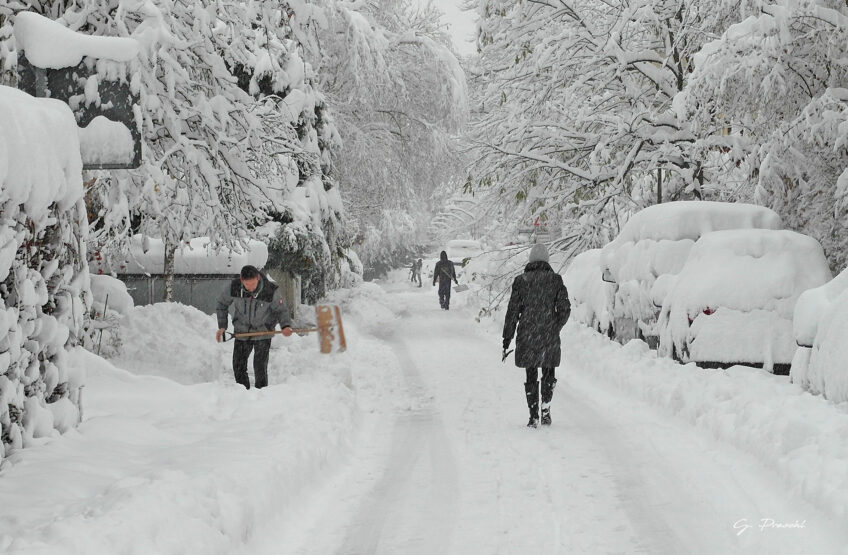 Nachbarn bearbeiten die Schneemassen in der Straße